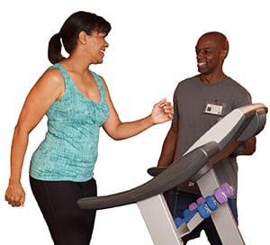 Person coaching another walking on treadmill.