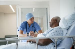 In hospital, patient in rests in a hospital bed while talking with health care provider before surgery.