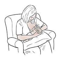 Female breastfeeding premature baby in cross-cradle hold.