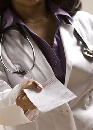 Doctor holding out written prescription.